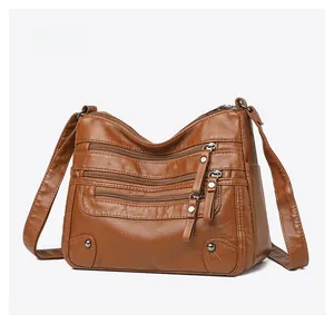 Detail of brown pebbled PU leather crossbody bag with multiple functional zip pockets