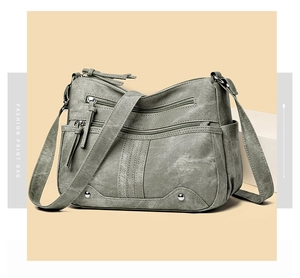 Détail d'un sac bandoulière vintage vert avec plusieurs poches zippées et des rivets