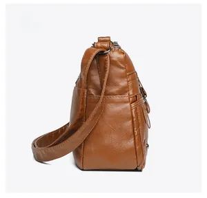 Side view of caramel brown soft leather crossbody bag with multiple zipper pockets