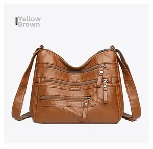 Detail of yellow brown vintage faux leather crossbody bag with triple front zipper pockets