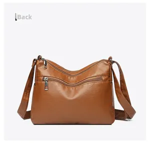 Rear view of brown textured soft leather crossbody bag with dual metal zipper pockets