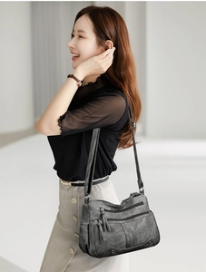 Détail d'un sac bandoulière rétro gris en cuir texturé avec poches zippées et glands