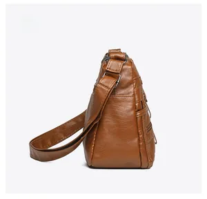 Side view detail of brown soft leather shoulder bag with multiple zipper compartments