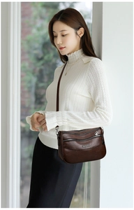 Detail of dark brown leather crossbody bag featuring three independent metal zipper layers