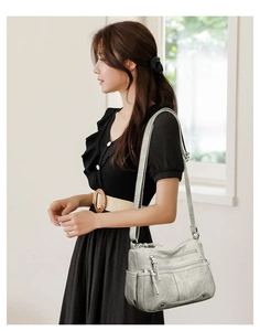 Détail du sac en cuir gris-vert à plusieurs zips montrant la texture souple et les poches