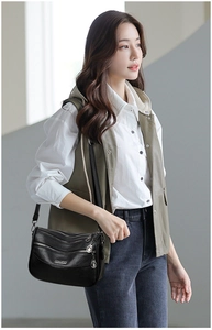 Detail of multi-layered black faux leather crossbody bag with three metal zippers