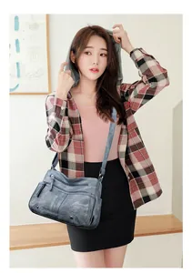 Sac bandoulière bleu gris avec fermetures éclair et rivets porté par un mannequin en style