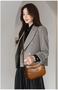 Detail view of a brown multi-layer crossbody bag with adjustable strap and metal logo