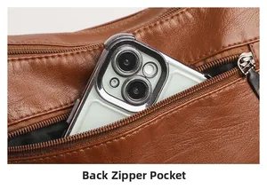 Detail of the rear zipper pocket on a brown leather shoulder bag with a smartphone inside