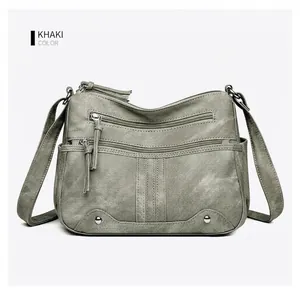Détail du sac à main kaki en similicuir avec plusieurs zips et pompons