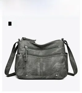 Vue détaillée d'un sac bandoulière gris à fermetures éclair et texture simili cuir