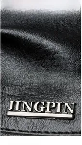 Detail of premium black lychee texture leather and silver JINGPIN metal logo on a handbag