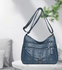Detail of navy blue woven leather crossbody bag with multiple zippers and rivets