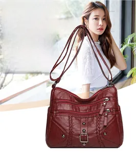Close-up of wine red crossbody bag with braided leather straps and metallic zipper details