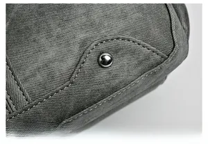 Détail du sac en toile grise montrant la double surpiqûre blanche et un rivet argenté