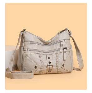 Detail of beige woven crossbody bag with textured leather, zip pockets and retro rivets