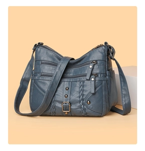 Detail of woven blue leather crossbody bag with multiple zippers and vintage metal rivets