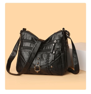 Detail view of black woven crossbody bag with multiple zippers and soft leather texture