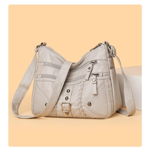 Close-up of cream woven crossbody bag with multi-zipper pockets and soft leather texture