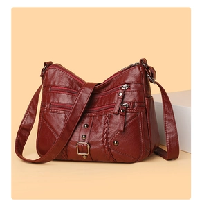 Detail of burgundy woven crossbody bag featuring multi-layer zippers and soft pebble leather
