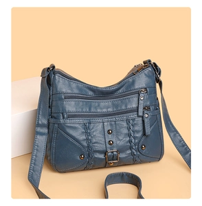 Detail of dark blue woven crossbody bag with multiple zip pockets and metal rivets
