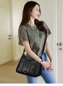 Close-up of black woven leather crossbody bag with triple zippers and metal rivets