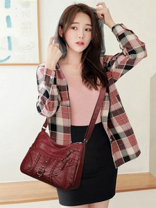 Detail view of burgundy woven crossbody bag with multiple zippers and rivets on soft PU leather
