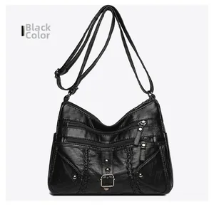 Detail of black woven leather crossbody bag with multiple zip pockets and metal rivets