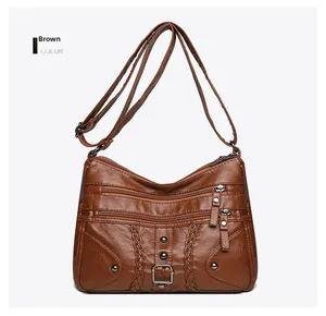 Detailed view of brown woven crossbody bag with multiple zippers and vintage metal rivets