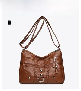 Detailed front view of brown woven crossbody bag with vintage rivets and zip pockets