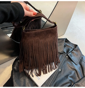Detail einer dunkelbraunen Wildleder-Beuteltasche mit langen Fransen und Goldschnallen