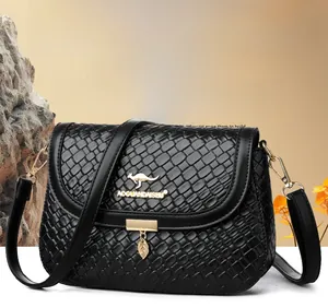 Detail of black woven square bag featuring golden kangaroo logo and leaf charm pendant