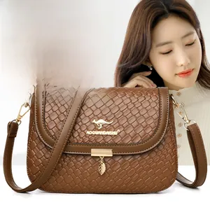 Close-up of brown woven texture bag featuring golden kangaroo logo and metal leaf pendant