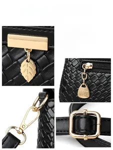 Detailed view of light gold leaf charm and kangaroo logo on black textured handbag