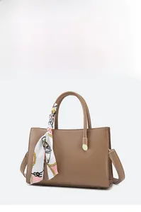 Close-up of brown litchi pattern leather tote bag with stylish silk scarf handle detail