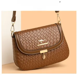 Detail of brown woven faux leather handbag featuring a gold kangaroo logo and leaf pendant
