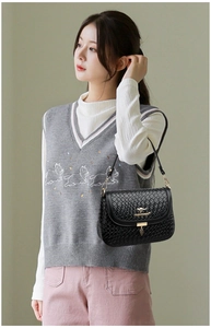 Detail of black woven texture leather handbag with golden kangaroo logo and leaf pendant