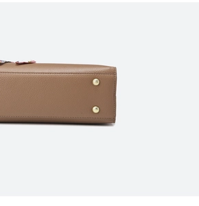 Detail view of brown lychee grain leather handbag base with protective gold metal feet