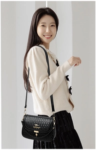 On-body view of a black crossbody bag featuring a woven texture and golden kangaroo logo