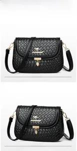 Close-up of black woven texture on a square bag with golden leaf charm and kangaroo logo