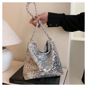 Detail of silver sequined handbag with unique braided rope handle in an artistic setting