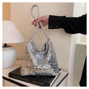 Close-up of silver sequin handbag featuring a unique braided rope handle on a book