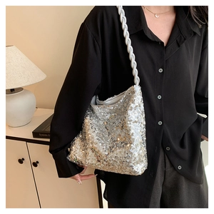 Detail of silver sequined handbag featuring a white chunky woven rope shoulder strap