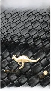 Detailed close-up of black woven leather texture with a gold kangaroo metal logo