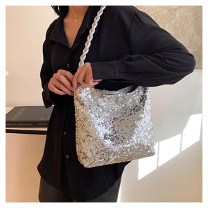 Close-up of silver sequin shoulder bag featuring woven leather strap and reflective finish