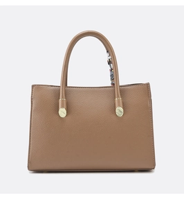 Close-up of tan leather tote bag with lychee texture and colorful silk scarf handle wrap