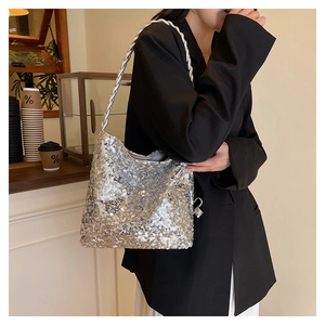 Detail of silver sequin handbag with twisted strap worn by model in a chic cafe setting