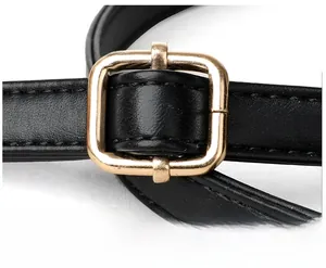 Close-up of black leather bag strap with adjustable gold square metal buckle and stitching