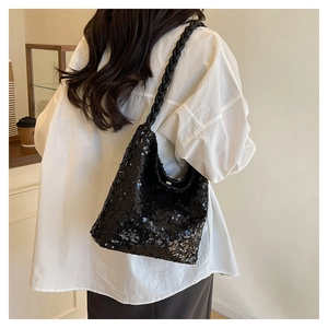 Detail of black sequined tote bag featuring a chunky woven shoulder strap on white shirt