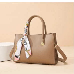 Close-up of brown litchi grain leather handbag featuring silk scarf wrapped handle